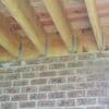 Under a deck view of a Metwood Deck Ledger Bracket attached to brick